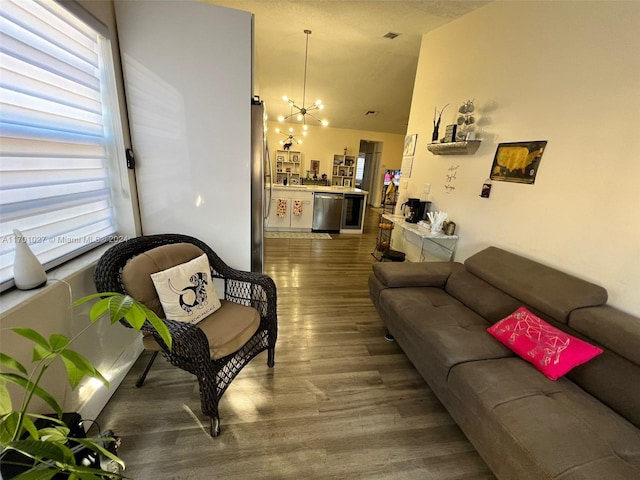 living room featuring a notable chandelier, dark wood-type flooring, and vaulted ceiling