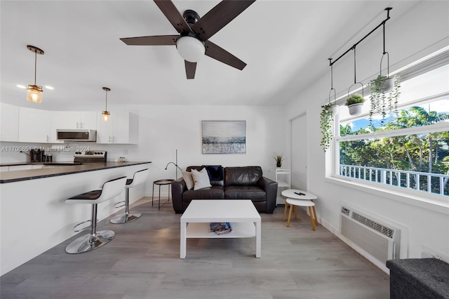 living room with light wood-type flooring, a wall unit AC, and ceiling fan