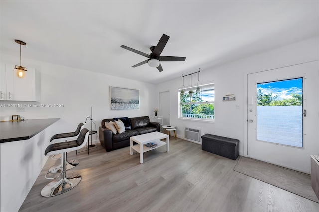 living room with ceiling fan, a healthy amount of sunlight, light hardwood / wood-style floors, and a wall mounted AC