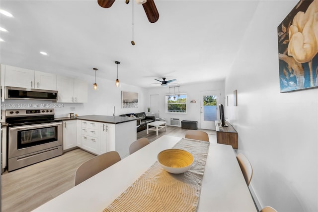 kitchen with stainless steel appliances, kitchen peninsula, pendant lighting, white cabinets, and light wood-type flooring