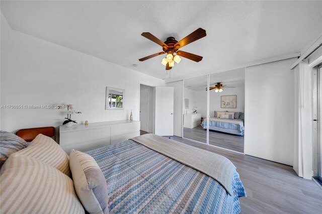 bedroom with ceiling fan, wood-type flooring, and a closet