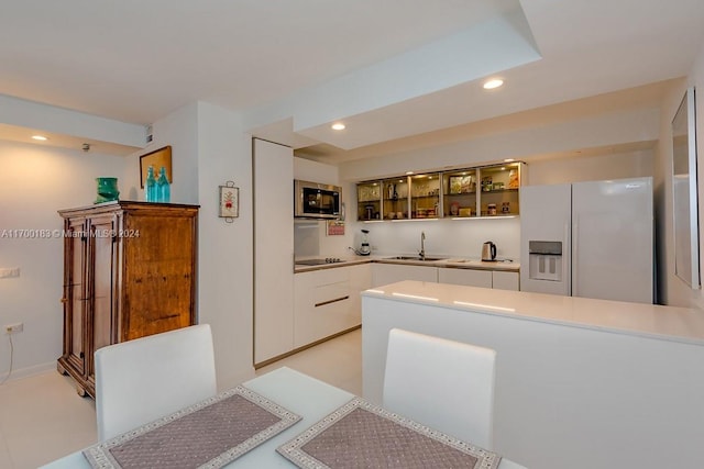 kitchen with white cabinets, black electric stovetop, white refrigerator with ice dispenser, and sink