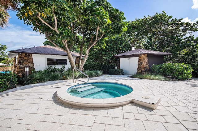 view of swimming pool featuring a storage unit, a patio area, and an in ground hot tub