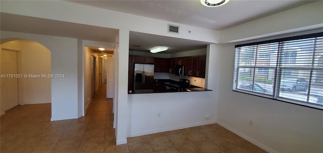 kitchen featuring kitchen peninsula, dark brown cabinets, light tile patterned floors, and stainless steel appliances