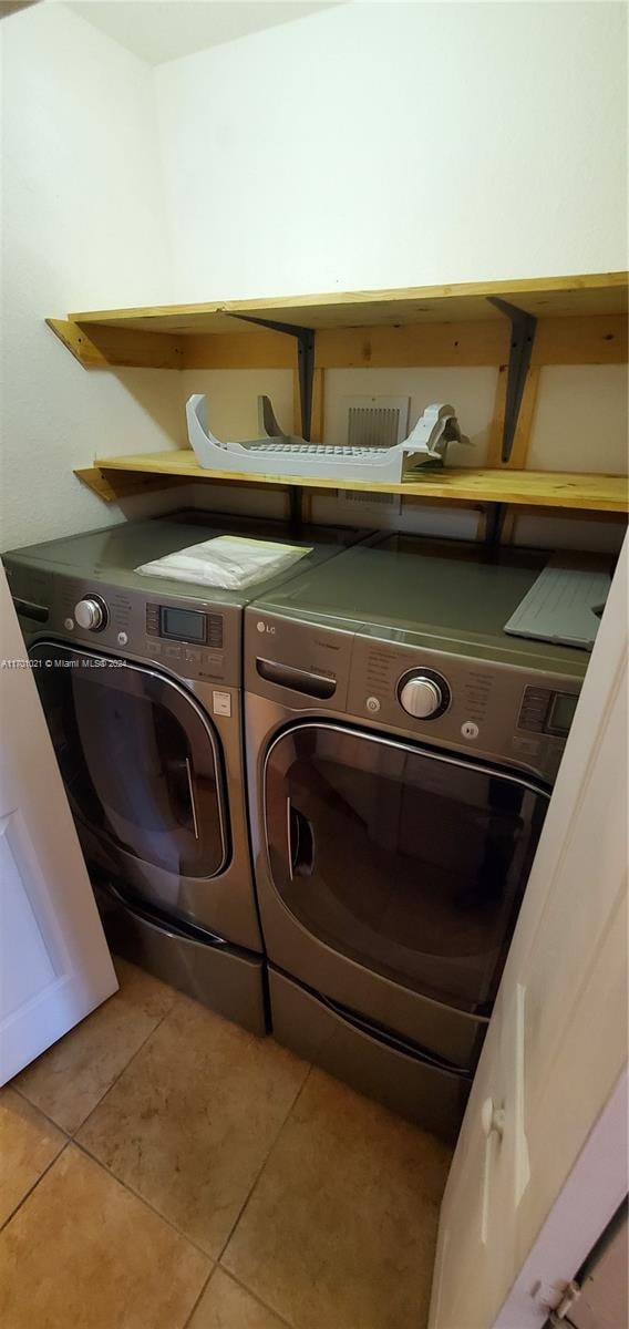 laundry room with washer and dryer and tile patterned flooring