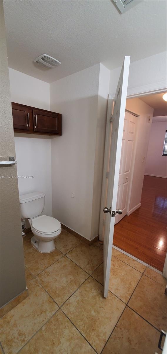 bathroom with toilet, wood-type flooring, and a textured ceiling