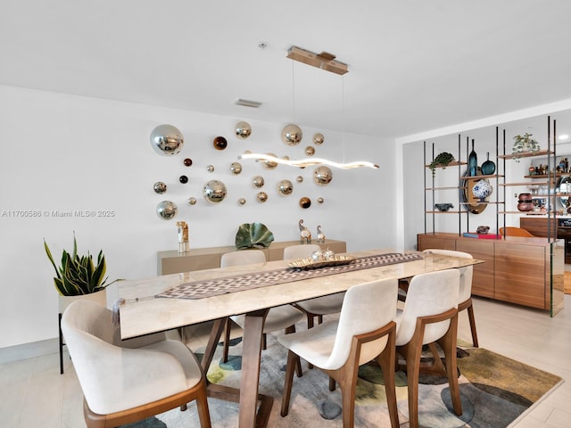 dining area with light wood-type flooring and visible vents