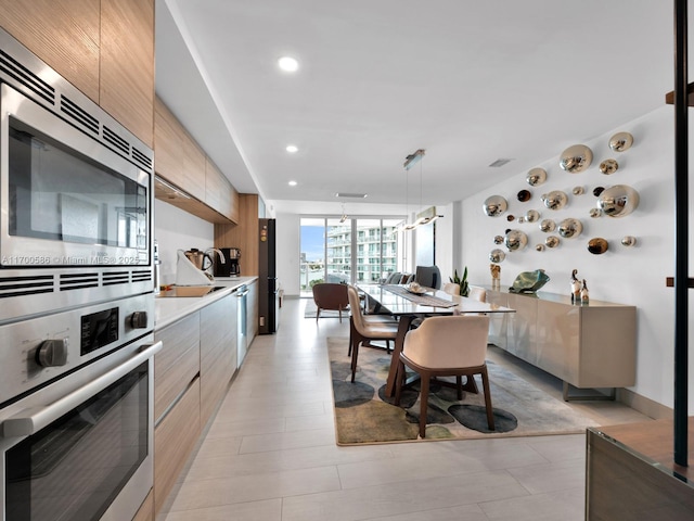 kitchen featuring hanging light fixtures, modern cabinets, appliances with stainless steel finishes, and light countertops