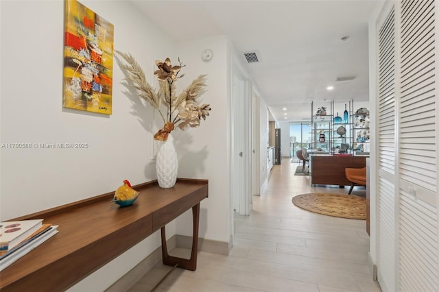 hallway featuring floor to ceiling windows, visible vents, and baseboards