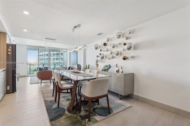 dining area featuring floor to ceiling windows, light wood-type flooring, visible vents, and baseboards