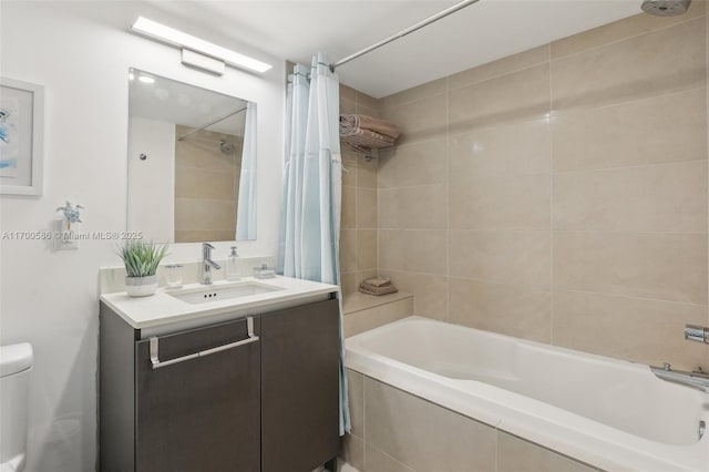 bathroom featuring tiled shower / bath, vanity, and toilet