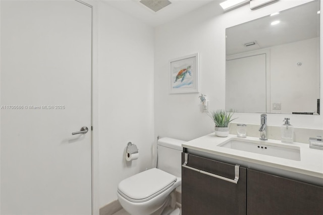 bathroom with toilet, visible vents, and vanity