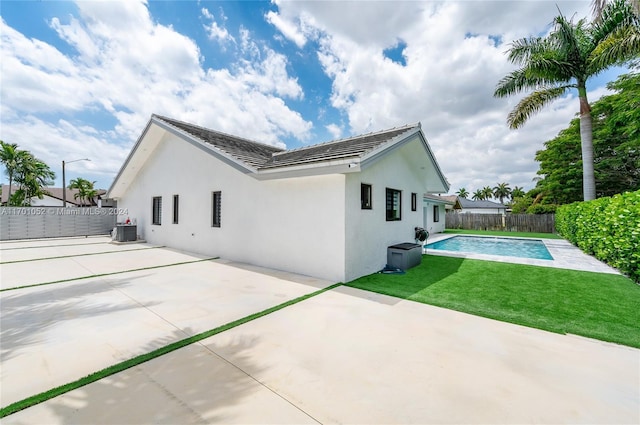 back of property featuring central air condition unit, a patio area, a lawn, and a fenced in pool