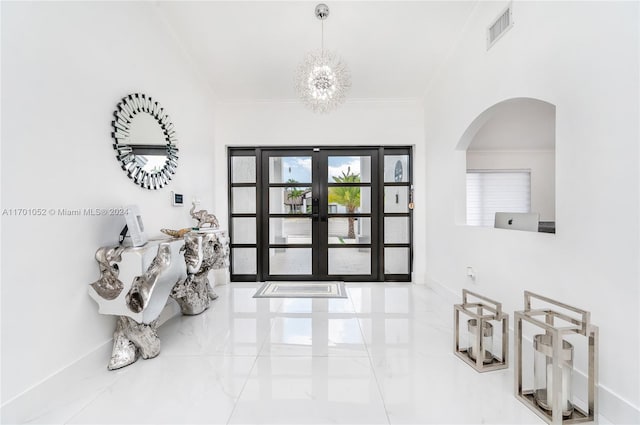 foyer entrance with crown molding, french doors, and a chandelier