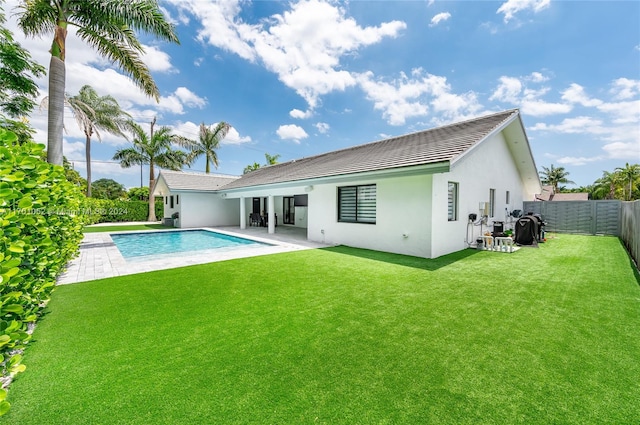 back of property featuring a lawn, a patio area, and a fenced in pool