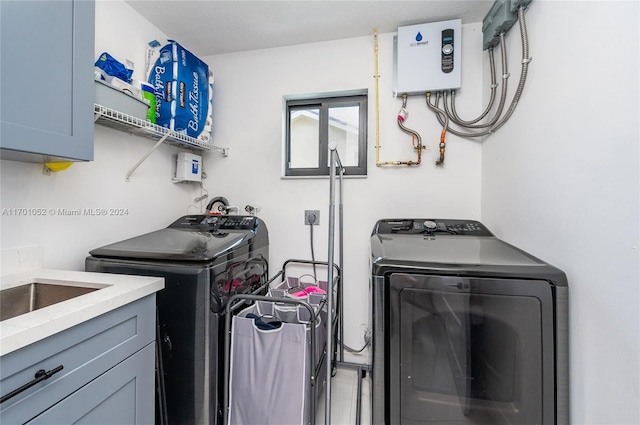 clothes washing area with water heater, cabinets, and independent washer and dryer