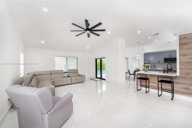 living room featuring ceiling fan, sink, crown molding, and vaulted ceiling