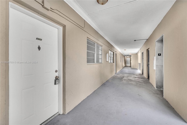 hallway featuring a textured ceiling, concrete flooring, and ornamental molding