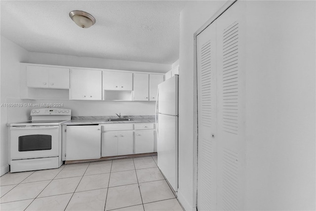 kitchen featuring white cabinetry, sink, a textured ceiling, white appliances, and light tile patterned flooring