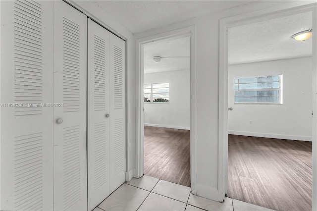 hall featuring plenty of natural light, a textured ceiling, and light wood-type flooring