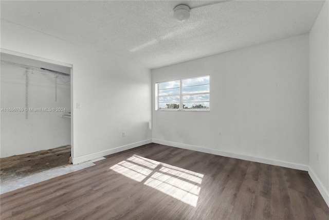 unfurnished bedroom featuring a textured ceiling, dark wood-type flooring, and a closet