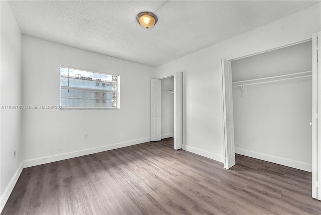 unfurnished bedroom featuring a textured ceiling, dark hardwood / wood-style floors, and a closet