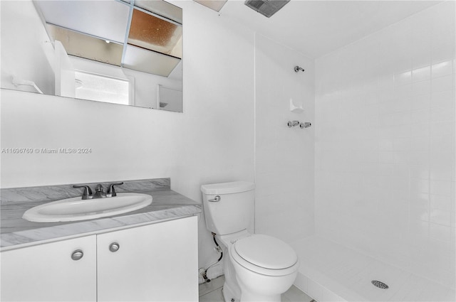 bathroom with a tile shower, tile patterned flooring, vanity, and toilet