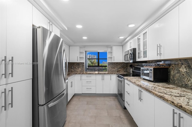 kitchen featuring appliances with stainless steel finishes, white cabinetry, dark stone countertops, and decorative backsplash