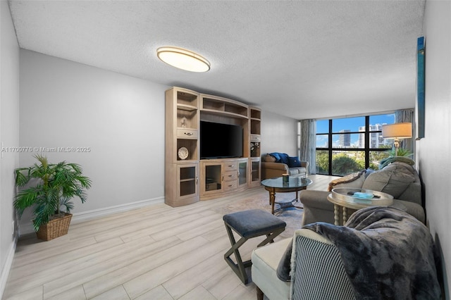 living room featuring a textured ceiling, light wood-type flooring, and expansive windows