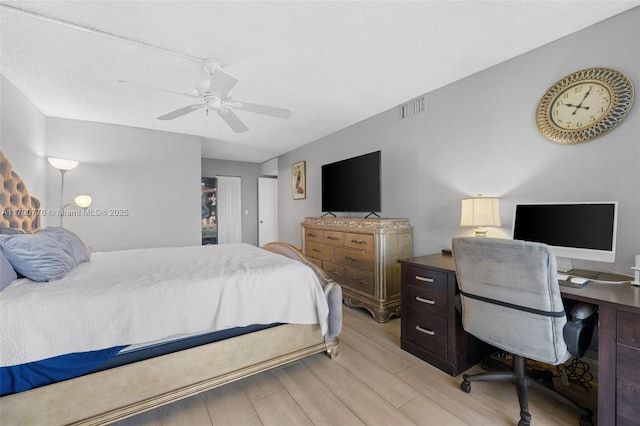 bedroom with ceiling fan, light hardwood / wood-style floors, and a textured ceiling