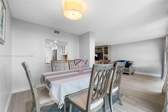 dining room featuring a textured ceiling and light hardwood / wood-style flooring