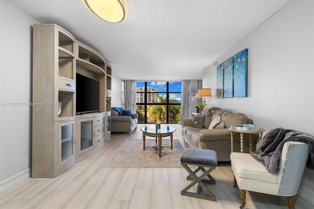 living room with a textured ceiling, a wall of windows, and light hardwood / wood-style flooring