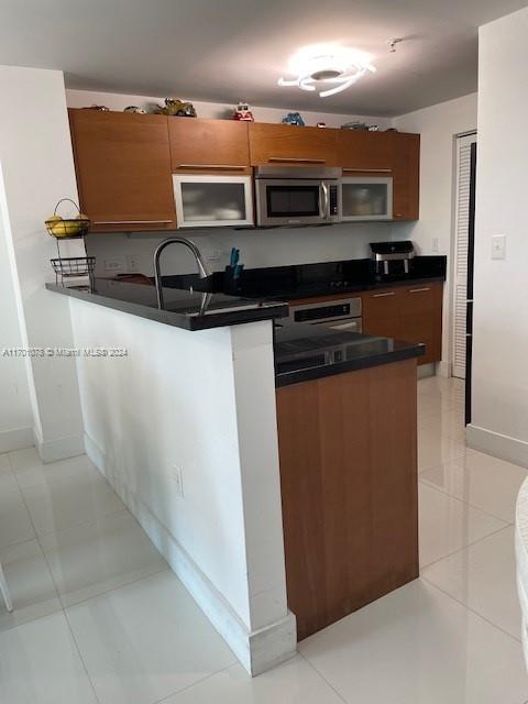 kitchen with kitchen peninsula, stainless steel appliances, and light tile patterned flooring