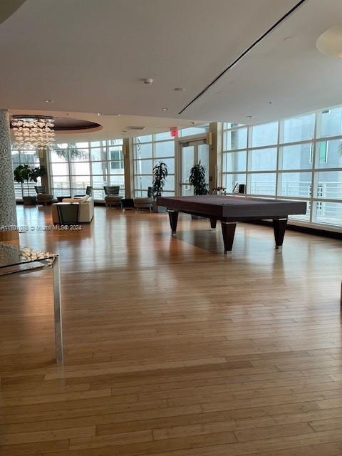 recreation room featuring floor to ceiling windows, plenty of natural light, hardwood / wood-style floors, and pool table