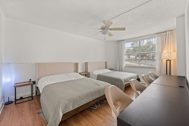 bedroom with ceiling fan, wood-type flooring, and a textured ceiling