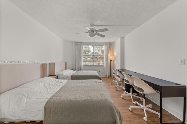 bedroom featuring ceiling fan, light hardwood / wood-style flooring, and a textured ceiling