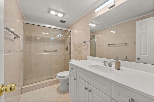 bathroom with tile walls, vanity, an enclosed shower, toilet, and a textured ceiling