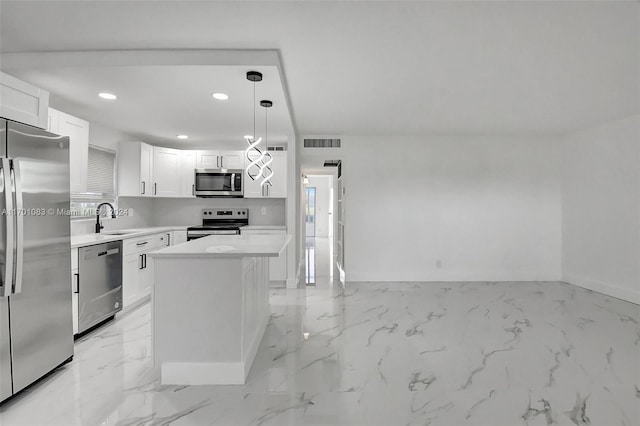 kitchen featuring a kitchen island, white cabinetry, stainless steel appliances, and hanging light fixtures