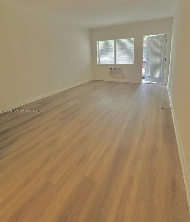 spare room featuring an AC wall unit and light hardwood / wood-style flooring