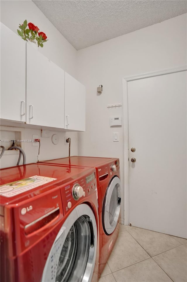 washroom featuring cabinets, light tile patterned floors, a textured ceiling, and washing machine and clothes dryer