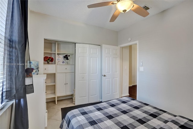 tiled bedroom with ceiling fan, a closet, and a textured ceiling