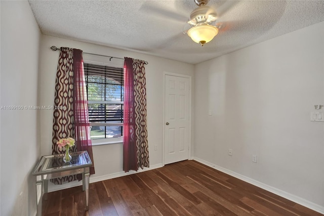 spare room featuring a textured ceiling, ceiling fan, and dark wood-type flooring