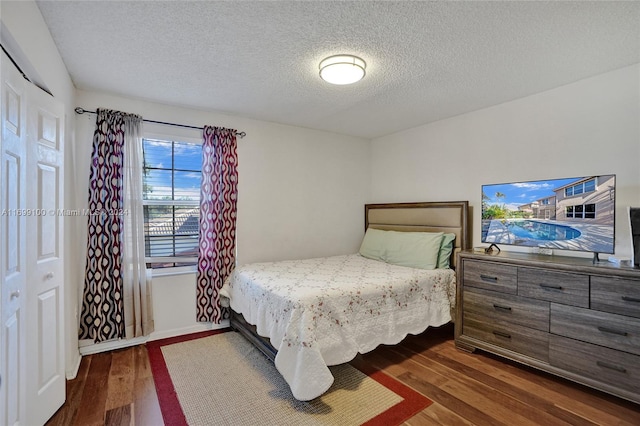 bedroom featuring dark hardwood / wood-style floors, a textured ceiling, and a closet