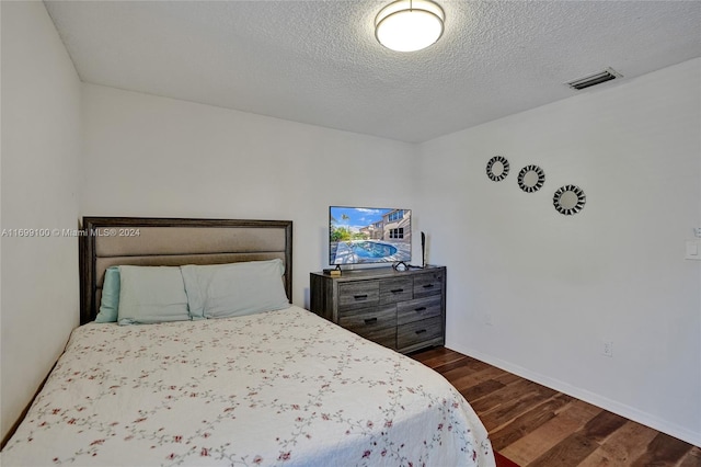 bedroom with dark wood-type flooring and a textured ceiling