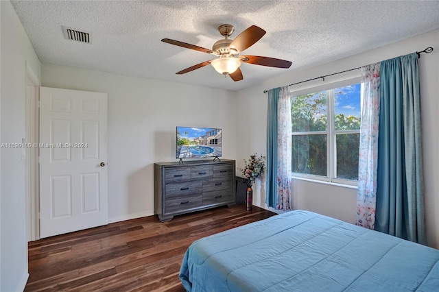 bedroom featuring ceiling fan, dark hardwood / wood-style flooring, and a textured ceiling