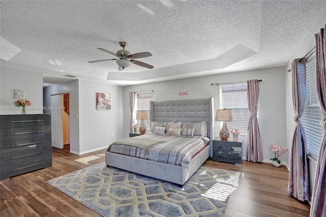 bedroom with ceiling fan, wood-type flooring, and a textured ceiling