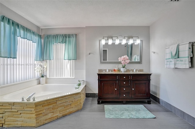 bathroom with vanity, a textured ceiling, and a tub to relax in