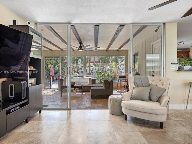 living room with ceiling fan, expansive windows, and a textured ceiling