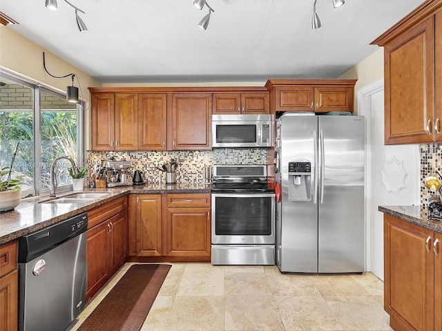 kitchen with backsplash, dark stone counters, sink, a textured ceiling, and appliances with stainless steel finishes