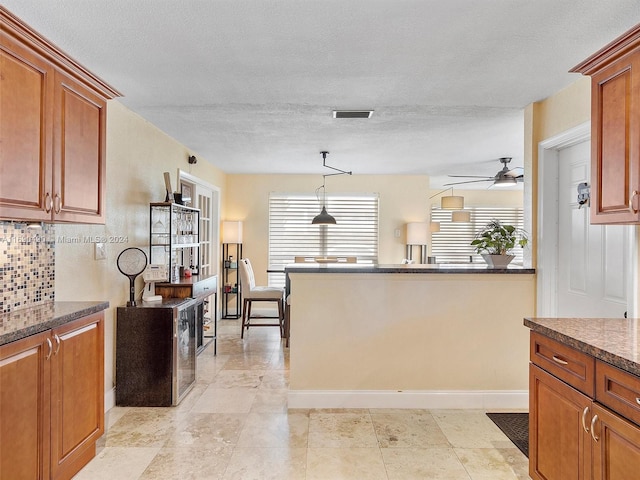 kitchen with ceiling fan, a textured ceiling, hanging light fixtures, and tasteful backsplash